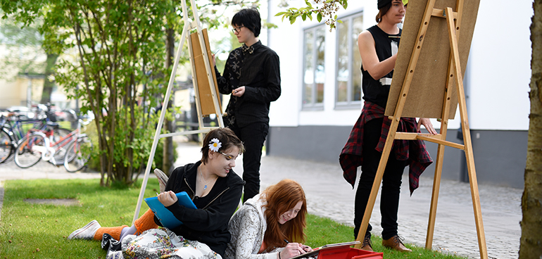 Elever från estetiska programmet står utomhus och målar